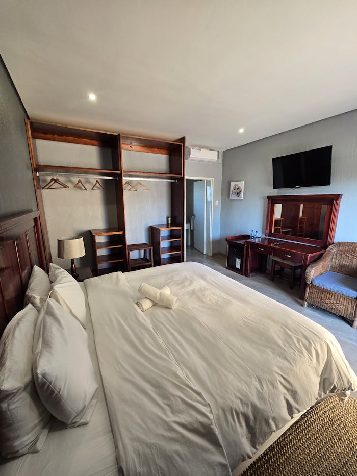 Spacious hotel room showcasing a king-size bed, TV, and wooden furniture.